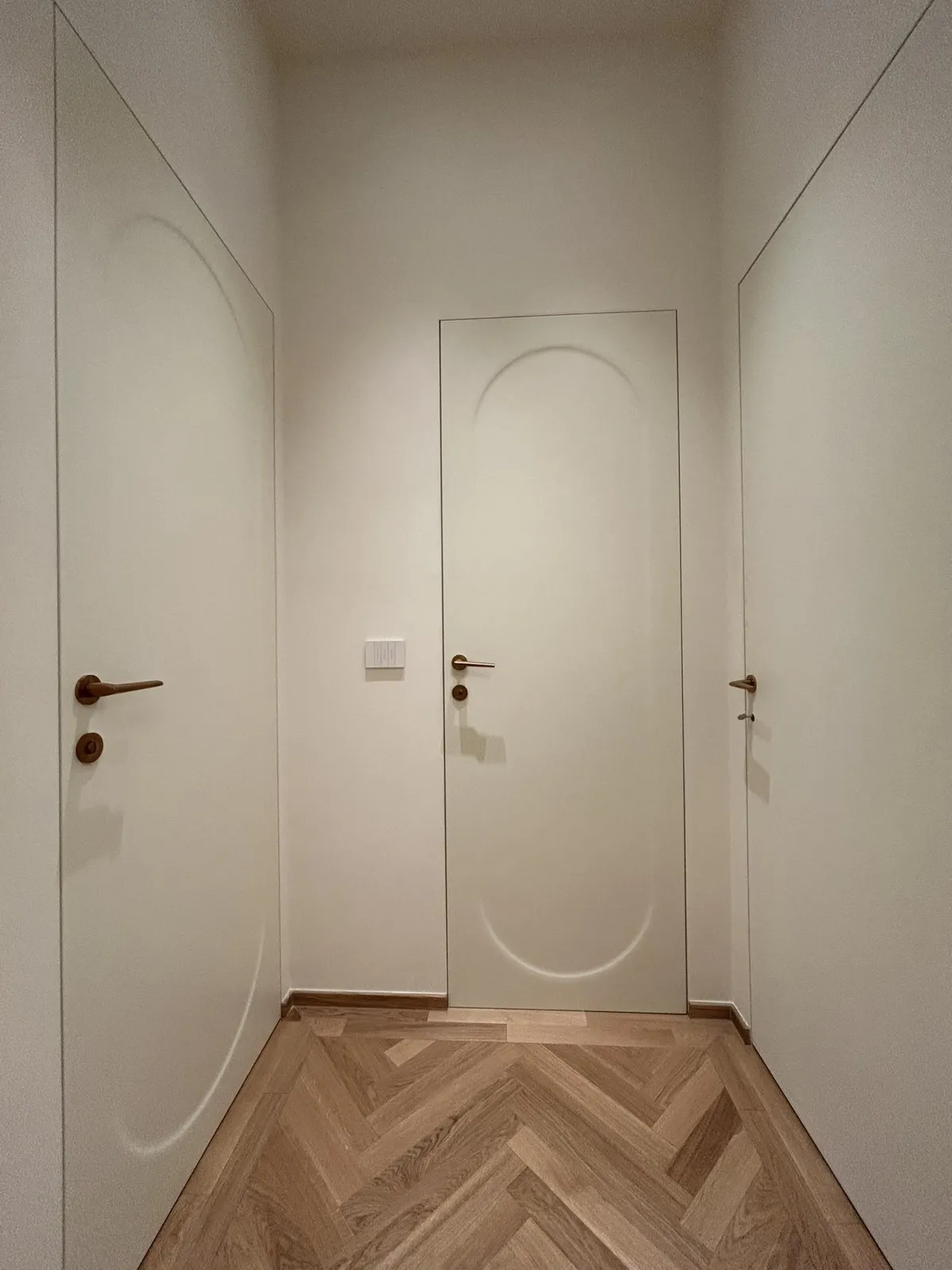 Porta interna filomuro bianca integrata nella parete in un corridoio con pavimento in parquet a spina di pesce - Tuttoporte Forlì.